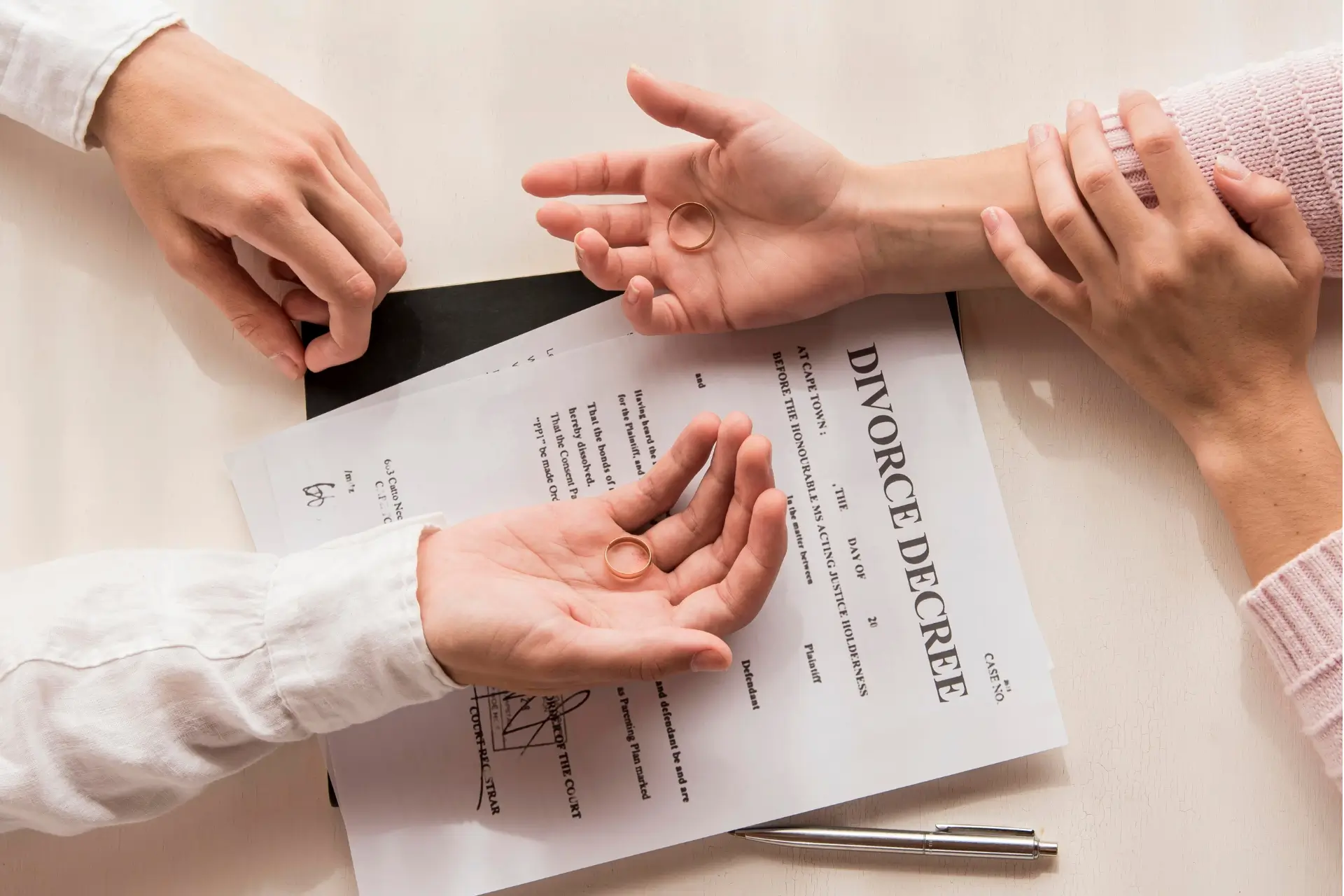 Wedding rings and a divorce decree document on a desk